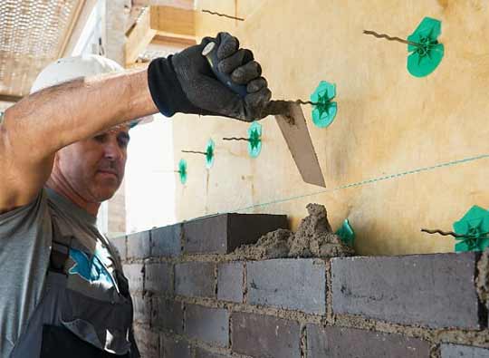 Maurermeister bei der Arbeit Maurermeister erbaut eine Mauer