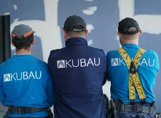 Trockenbaumitarbeiter Drei Trockenbaumitarbeiter mit dem Rücken auf einer Baustelle